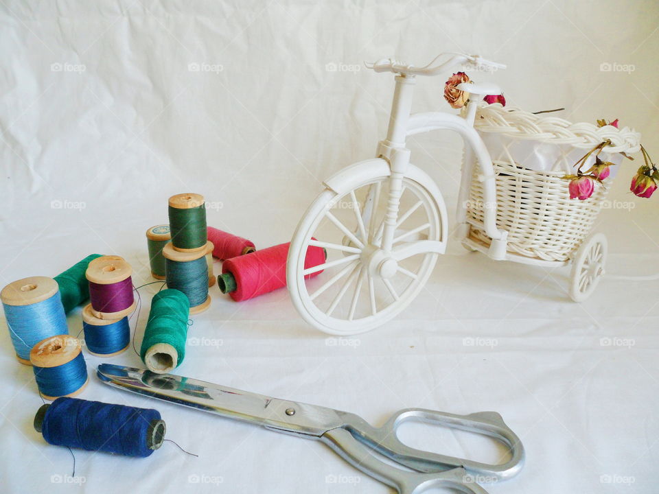 decorative toy bike, dried rosebuds and thread on white background