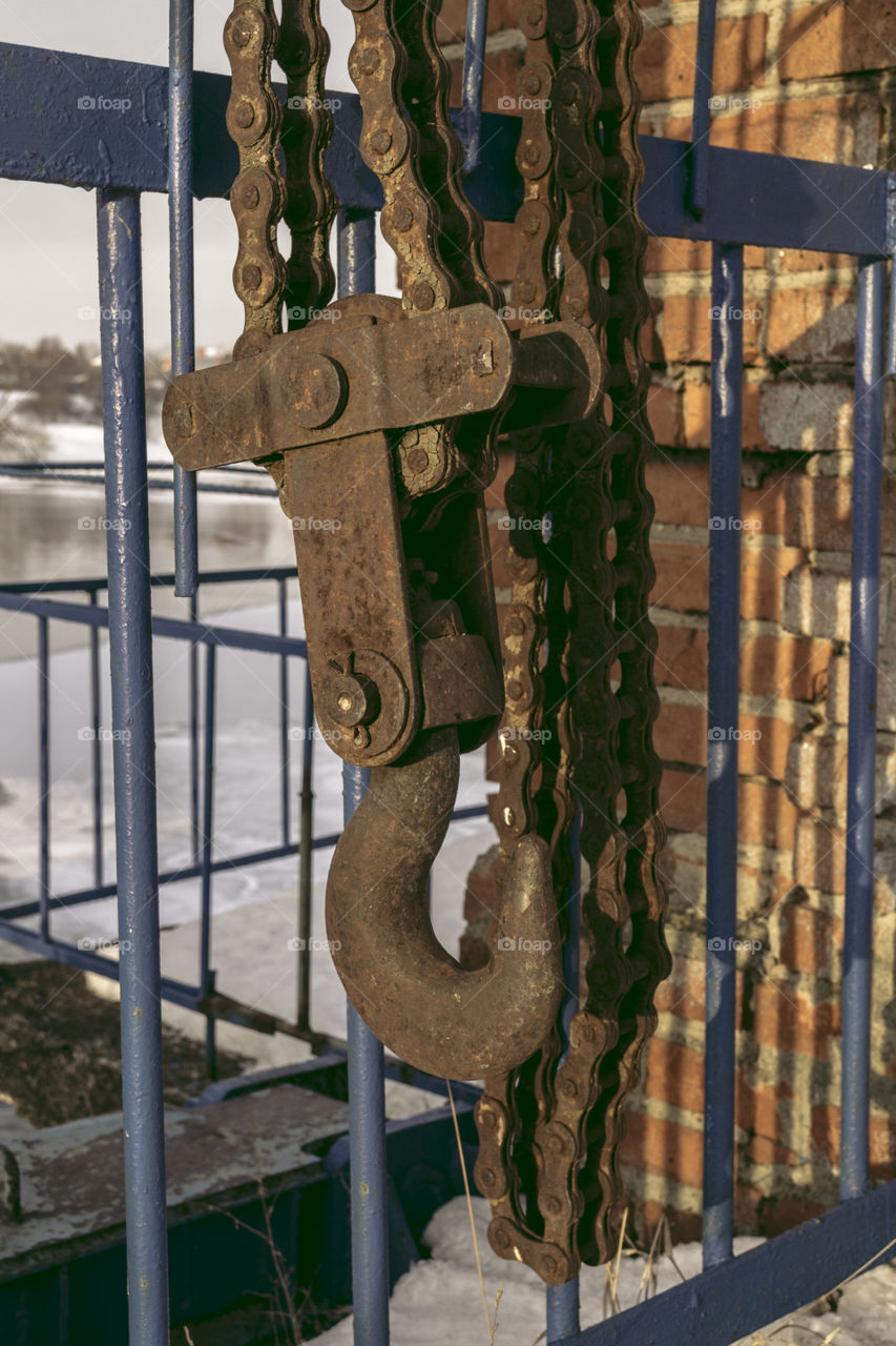 Conceptual faded giant industrial rusty hook and chains,