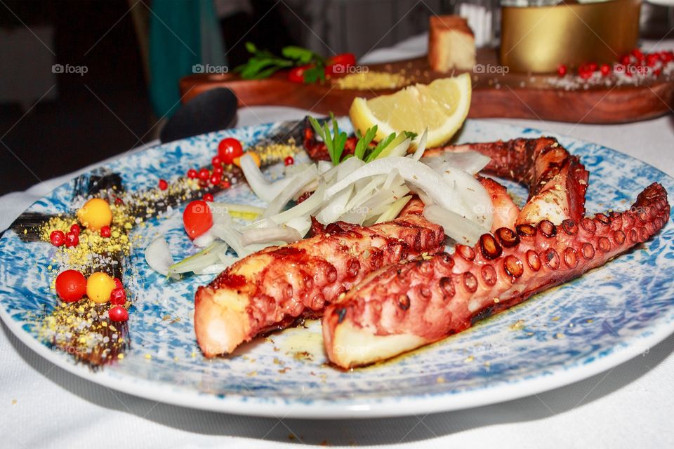 Grilled octopus dish with onion, lemon and tomatous