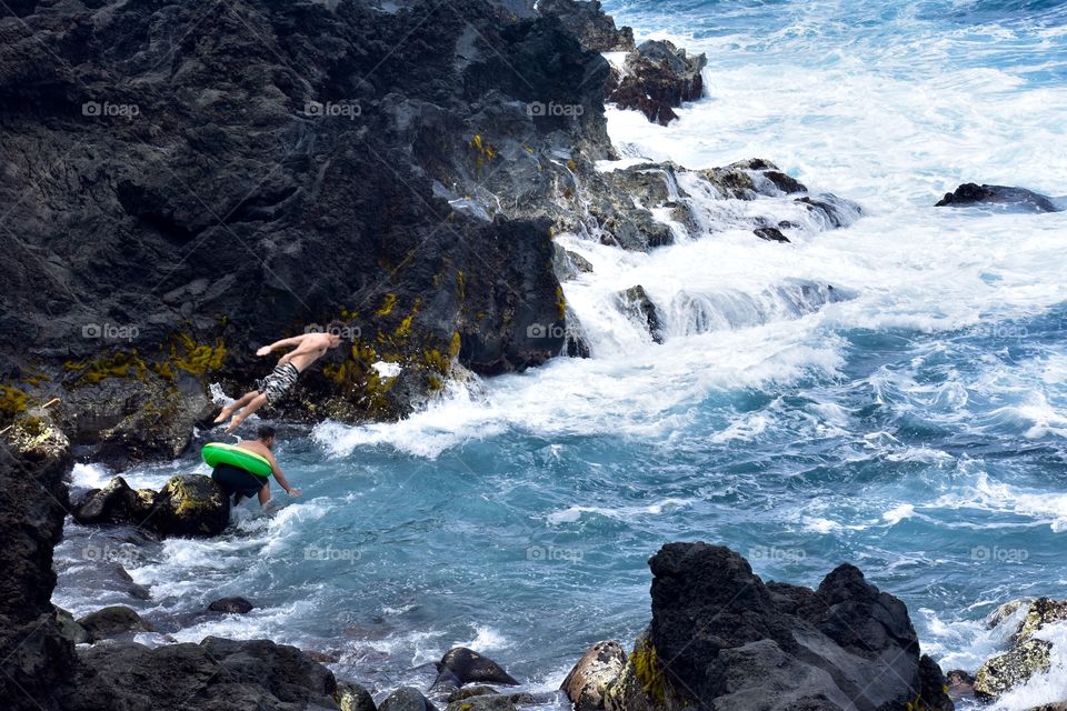 Kids diving and swimming along the sea cliffs on the east side of the Big Island of Hawaii.