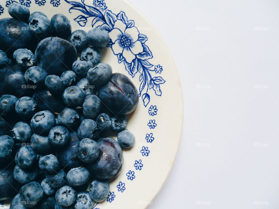 Berries of blueberries and plums on a white plate