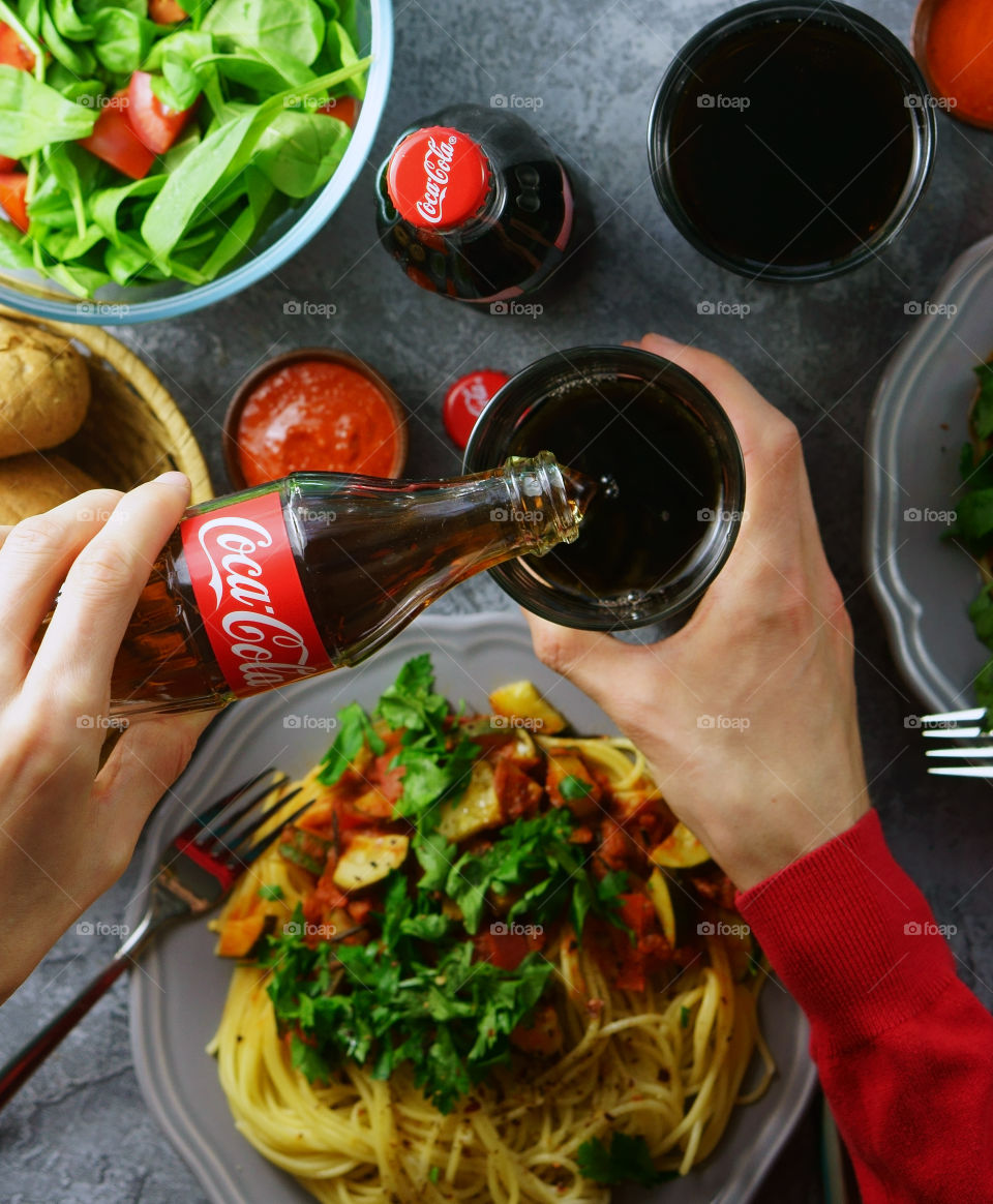 A person pouring coco-cola  in the glass