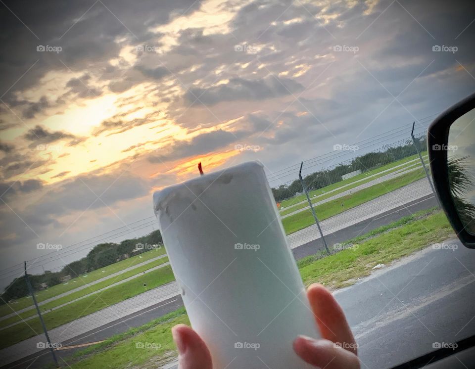 Candle Seems To Be Lit Up By The Sunset Through The Clouds Held Through The Vehicle Window.