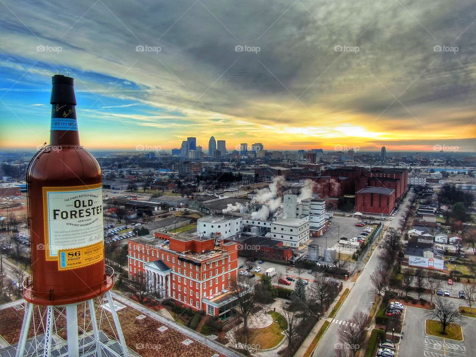 Sunrise at Brown Forman Distillery in Downtown Louisville. Old Forester bottle in the foreground and Downtown Louisville in the background.