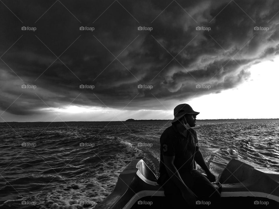 Fleeing from the thunder storm chasing behind. Boat speeding away to get away from the heavy clouds building behind. Rainy day, rainy season, the eastern monsoon time in the northern part of Sri Lanka.