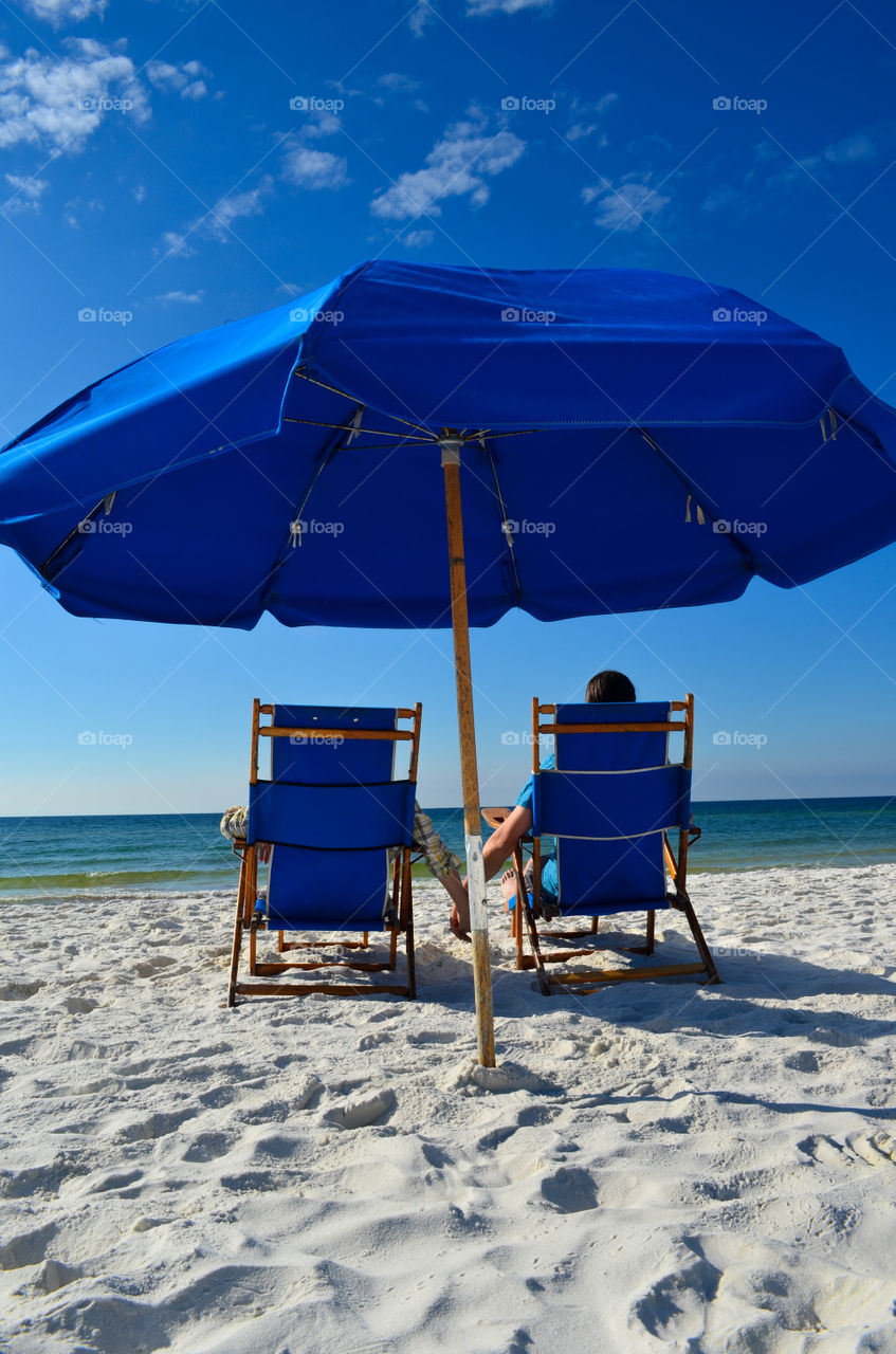 Couple holding hands at the beach under an umbrella