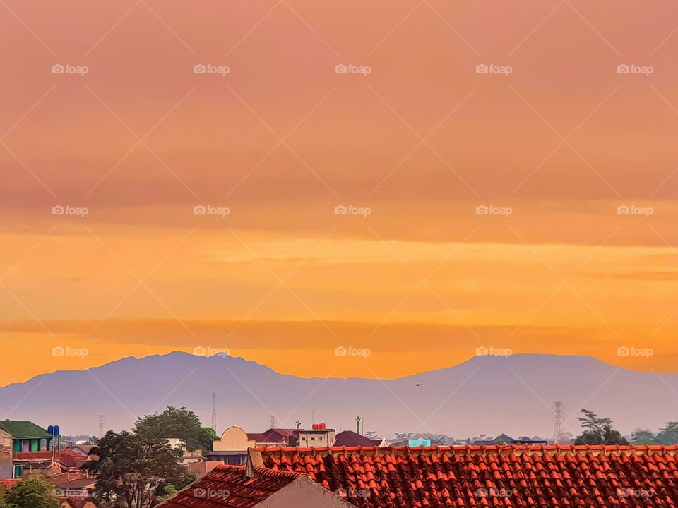 Sky is cloudy in morning, view in earl morning, sky is coverd by clouds and mist, the clouds are red and yellow, the fog cover view of mountain so that it looks gray