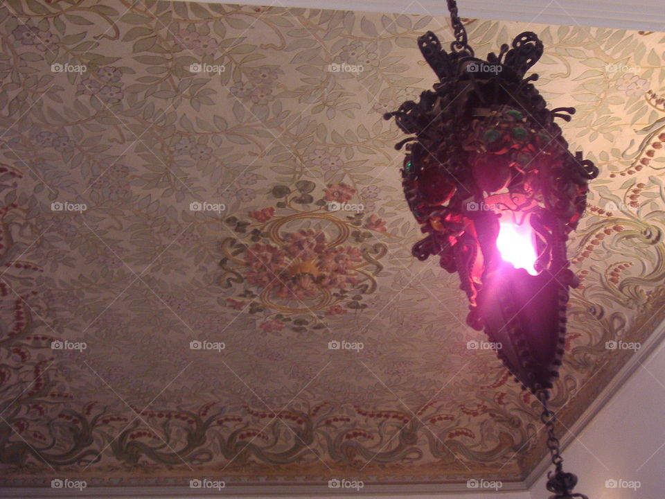 Unusual lamp with rose light on a decorated ceiling 