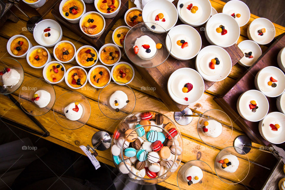 Delicious dessert table with pastries and biscuits, pudding and macaroons. Love the colors of the dishes served on a wooden table