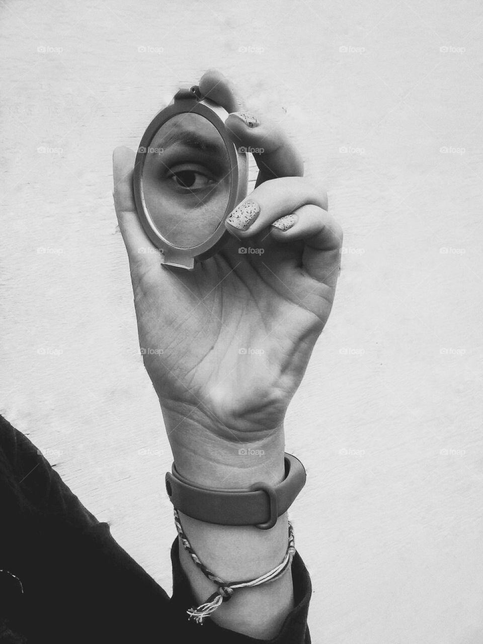 an original, conceptual photo, namely a black and white photo of a woman's eye in a small mirror, which is held in her hand
