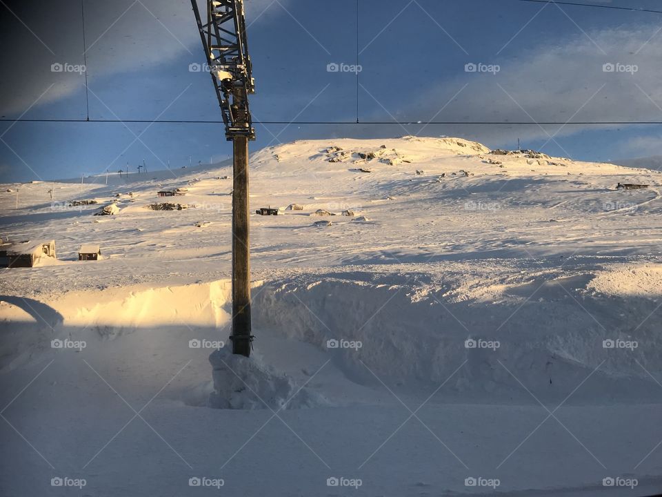 A snowy mountain beside the beautiful train tracks going from Bergen to Oslo. Snowy weather, but sunny and calm.