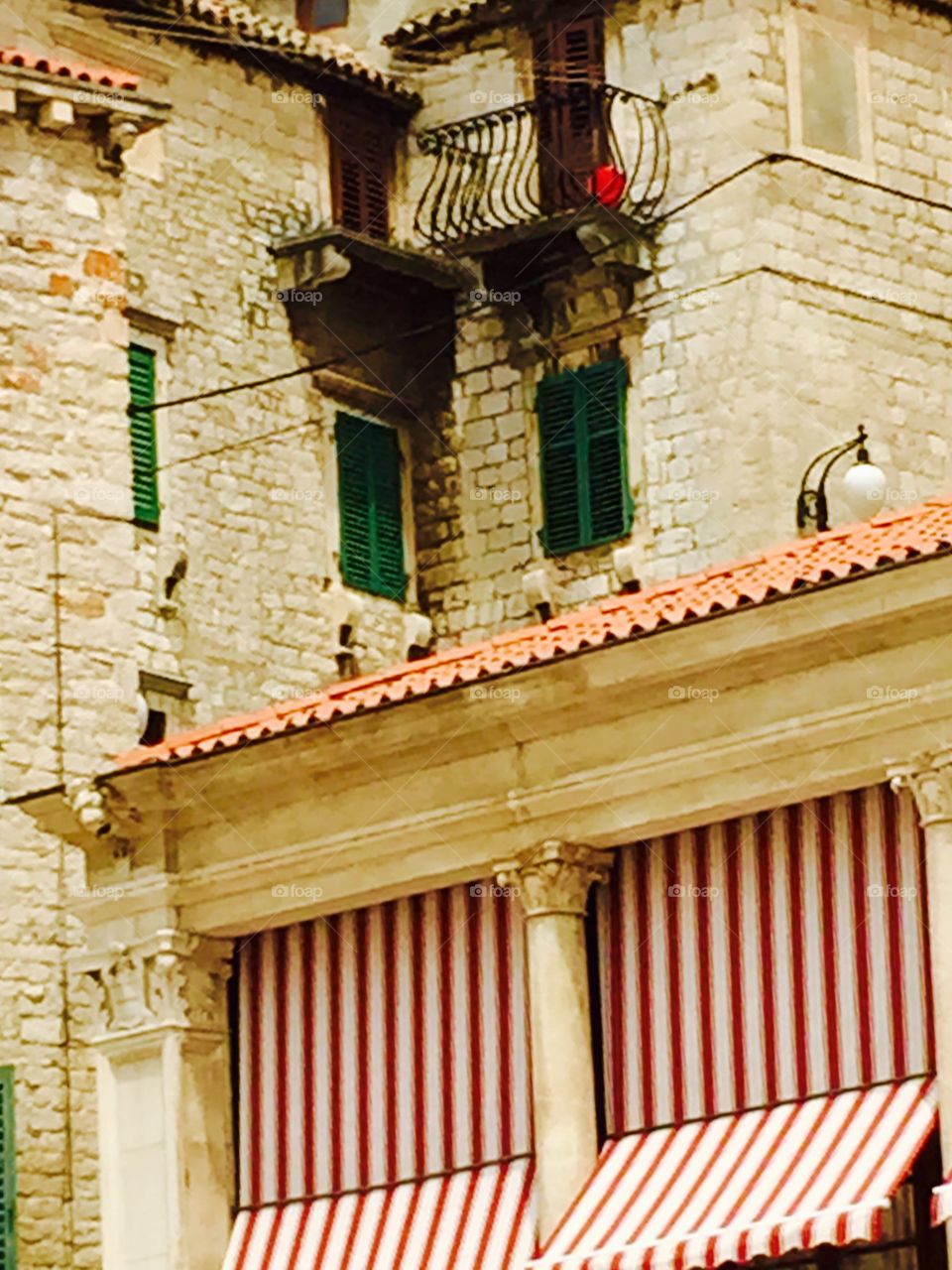 Red bucket on balcony . Walking in medieval town within Croatia this colorful item on balcony caught my eye 