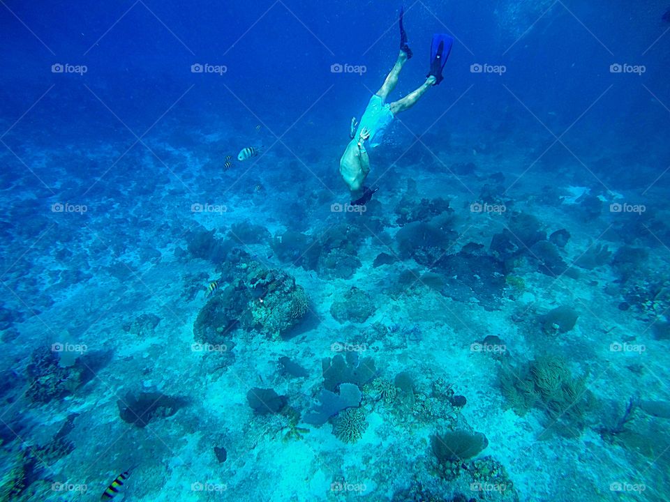 man going down into the deep blue caribbean sea