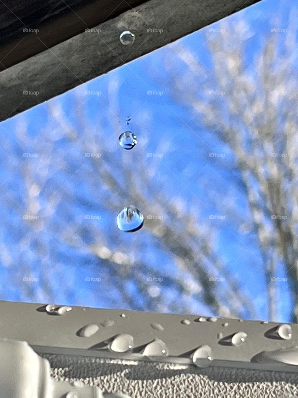 Droplets of water drip from the awning onto a door on a sunny winter day.