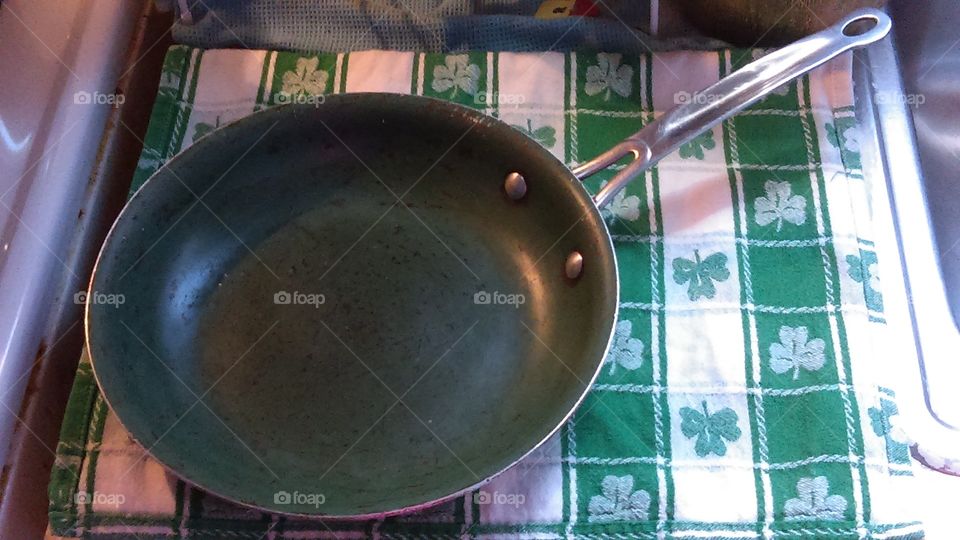 Green ceramic frying pan against a St. Patrick's day themed kitchen towel