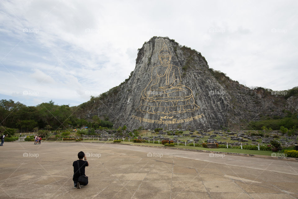 Man taking a photo of the engrave mountain in Thailand 