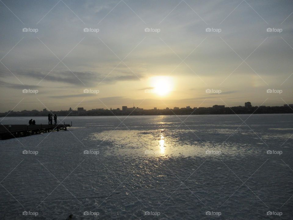 sunset in March, the ice on the river is not melting yet, but walking is dangerous, the sky is cloudy, the sun is shining