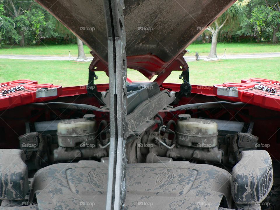 Under the hood of a red pickup truck with combination wrench set tools organized in a red tool hard case by the work station with its reflection from a mirror.