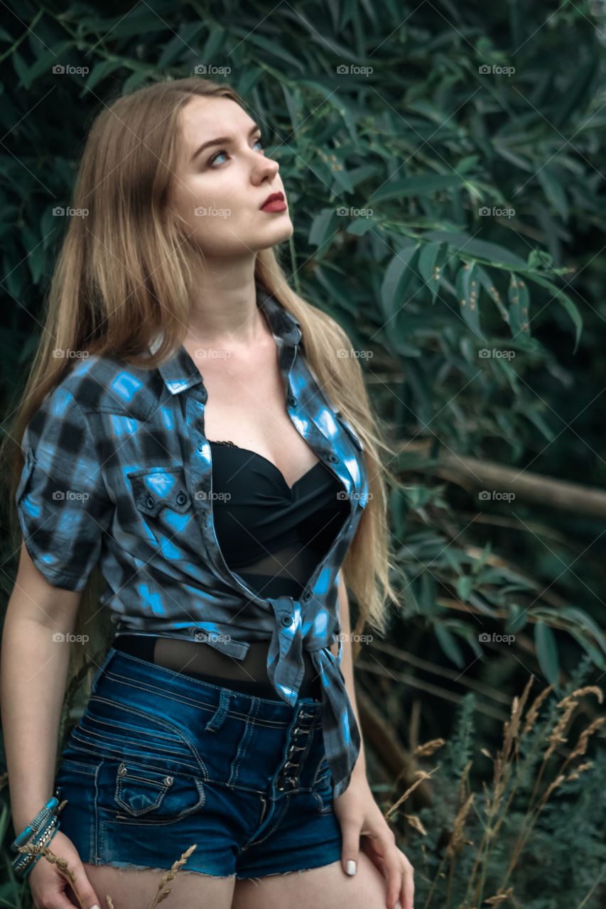 A girl with blond hair in a plaid shirt and short denim shorts on a background of trees and nature,
Girl, woman, man, people, blonde, blonde hair, checkered shirt, shorts shorts, denim shorts, forest, nature, trees, grass, feelings, emotions, tenderness, love, lifestyle, lifestyle, recreation