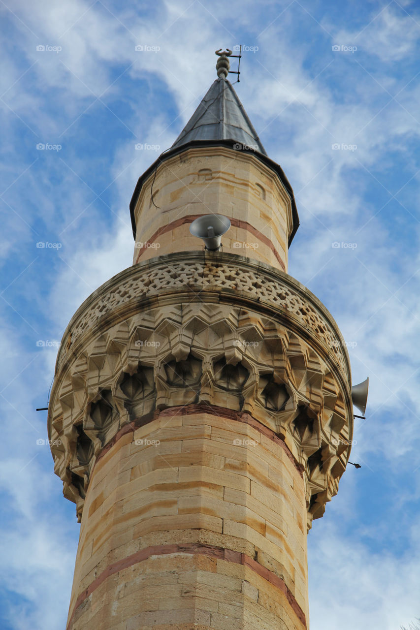 Minaret with loudspeakers against sky