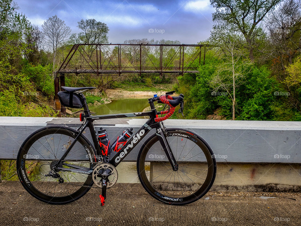 A cyclist takes a break along a route at a River crossing with a historic truss bridge
