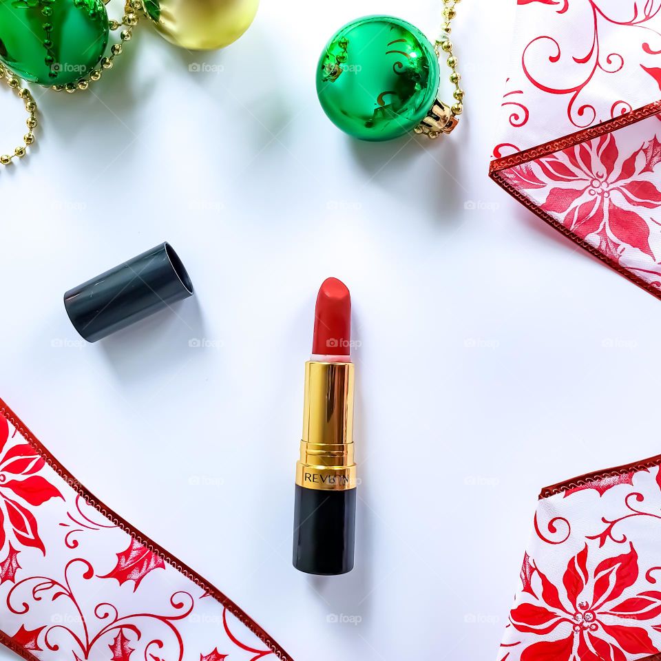A vivacious red lipstick flatlay in a red, white and green holiday inspired theme.