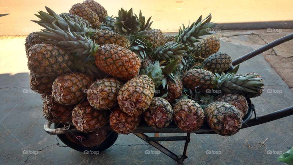 Deliciosos abacaxis em um carrinho de mão/carriola. De vendedor ambulante.