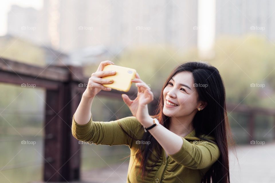 Happy Asian woman using mobile phone outdoor 