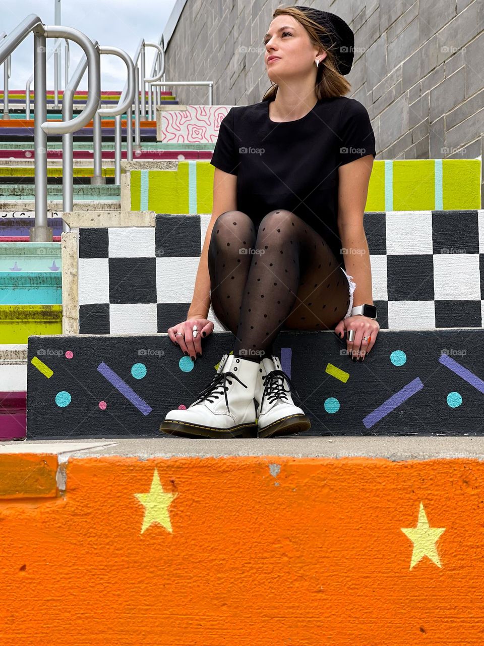 Woman sitting on colorfully painted cement steps wearing white 1490 Dr. Martens boots 