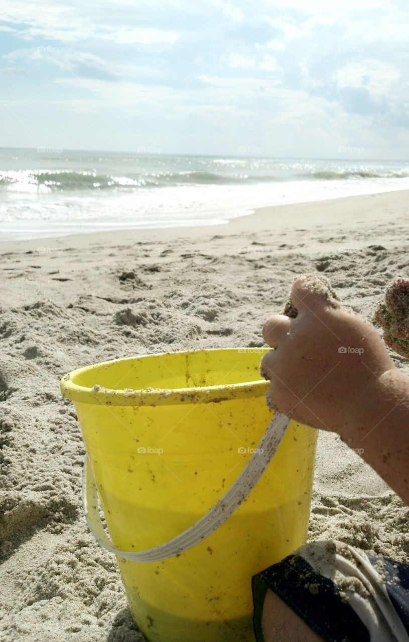 Child on beach with yellow bucket