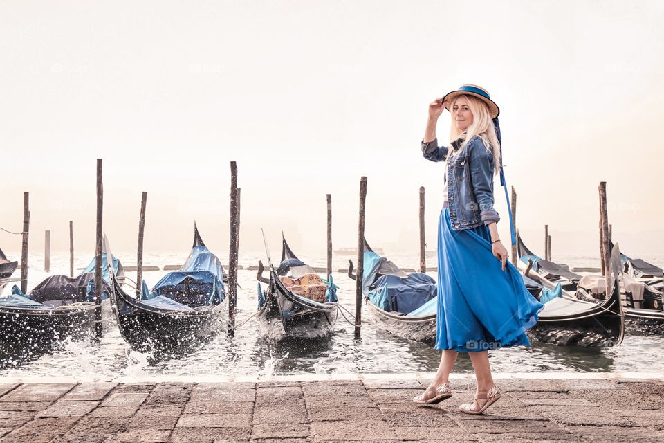 Woman in a blue dress on a background of gondolas in Venice