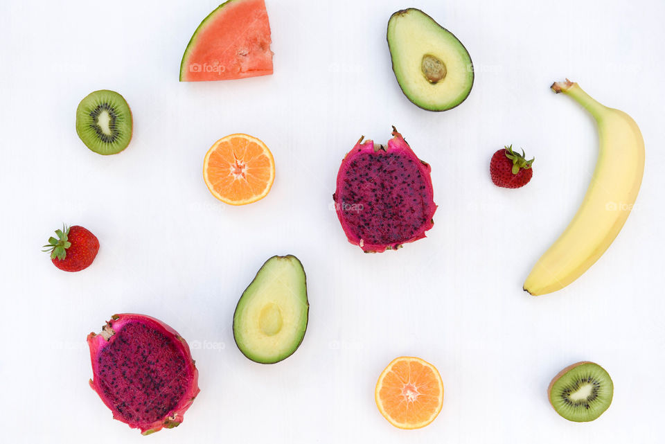 Flat lay of assorted colorful fruits spread out on a white tabletop