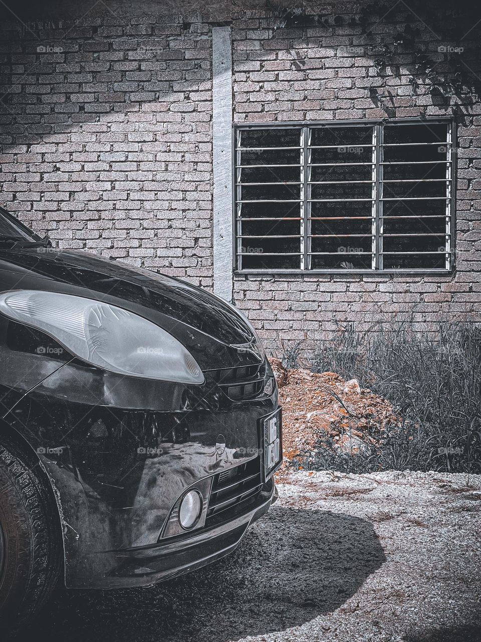 Small car black in colour with vintage surrounding and a window as a background 
