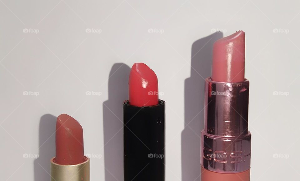 Pink and red lipsticks and shadows against a white background