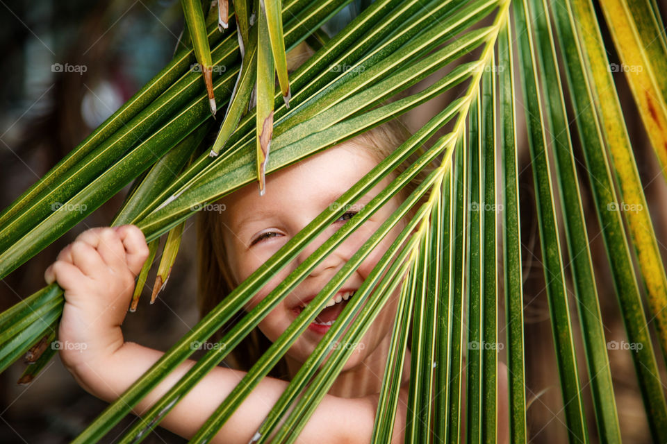 Cute laughing little girl and palm leaf