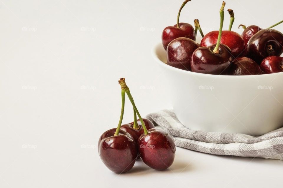 Delicious cherries in white bawl on white background