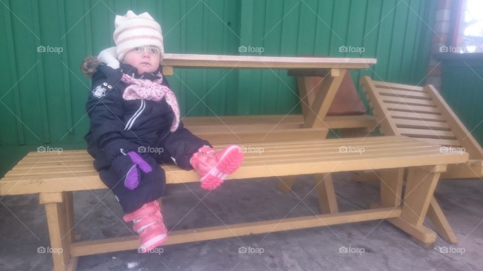 waiting for summer. cute toddler sitting in grilling corner during the winter