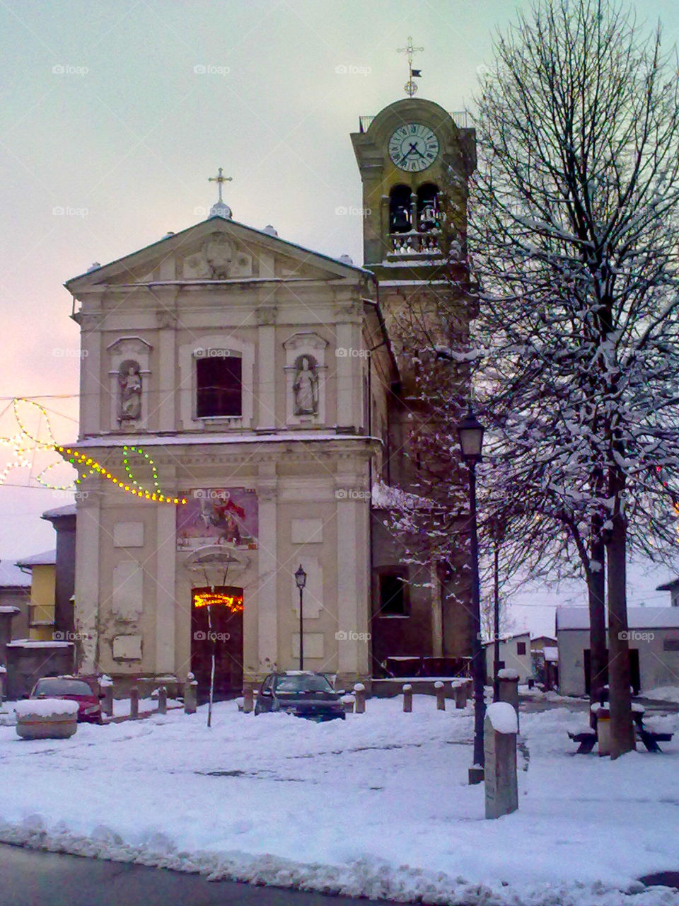 Italian church in a small village during the winter with snow  at the sunset light. Italy 