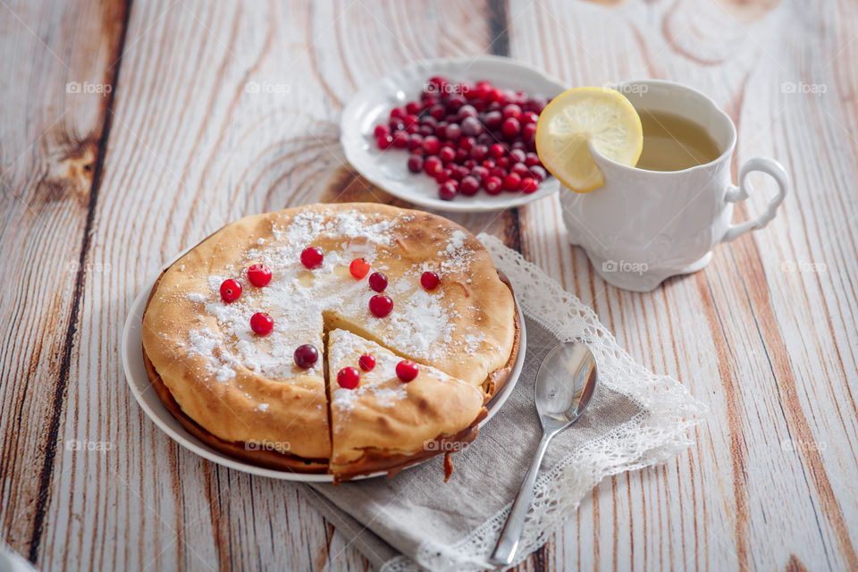 Cheesecake with cranberries and sugar on wooden background