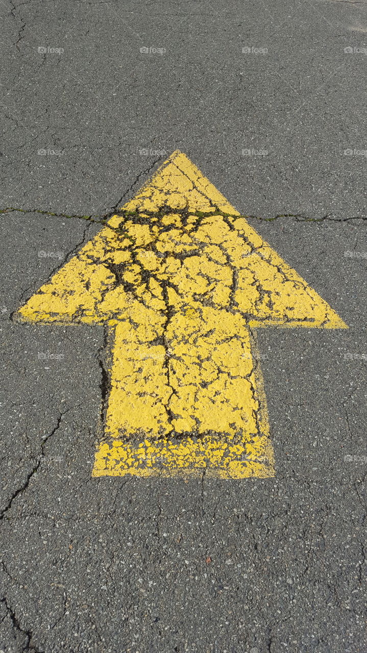 a yellow arrow painted on a roadway