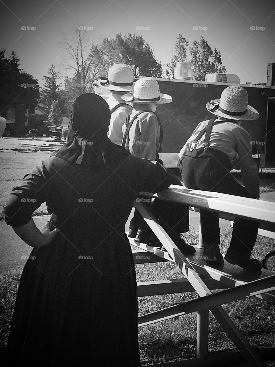 An Amish mother and her three sons in black and white. 