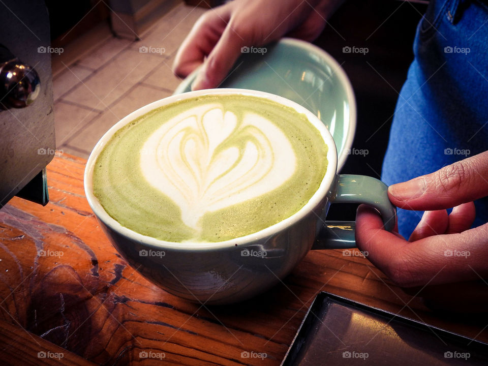 Cafe Worker Preparing A Green Tea Cappuccino With Heart Design At A Cafe