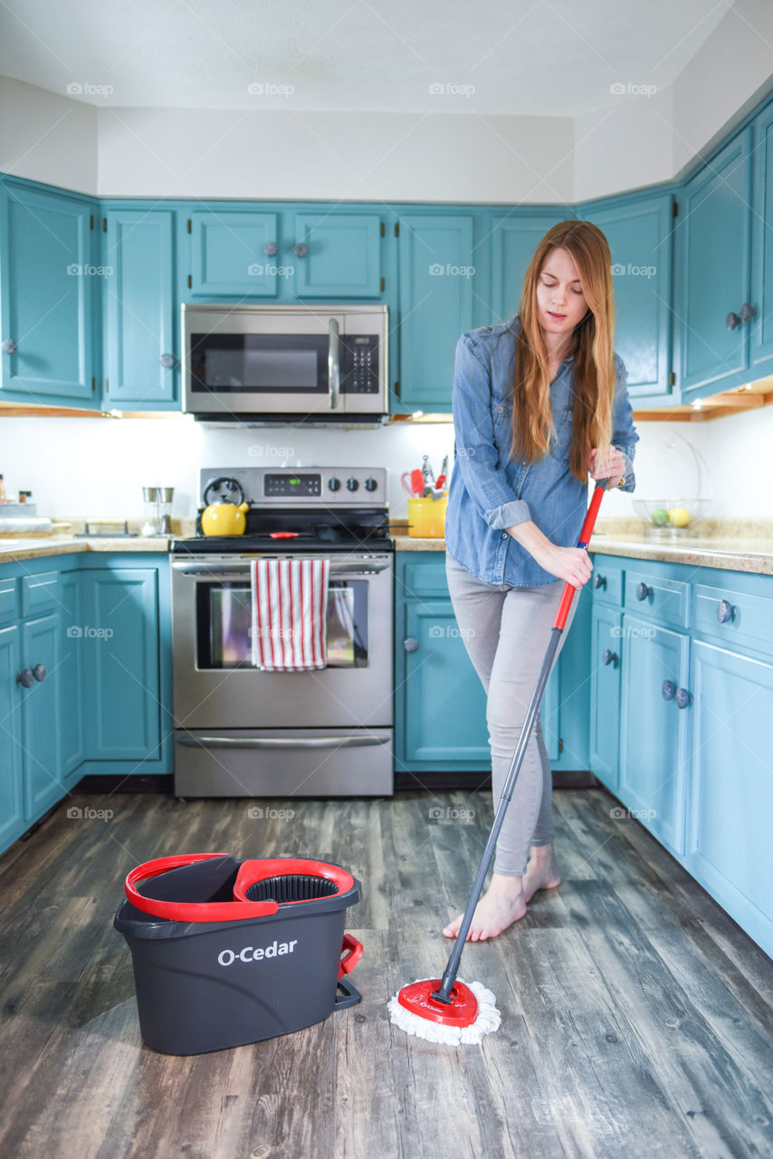 Young woman mopping a kitchen floor