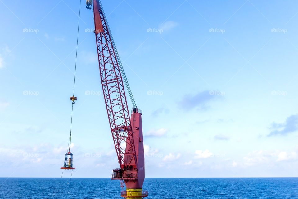 Offshore worker transferred from a construction barge to a tug boat using personal transfer basket at oil field