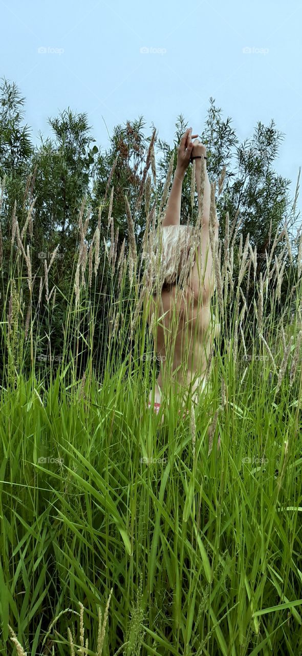 девушка с обнаженной спиной стоит в высокой траве