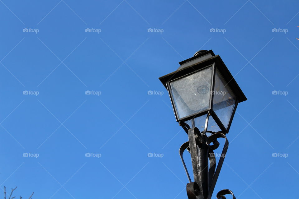 Isolated vintage lamppost on a blue sky in Autumn close-up