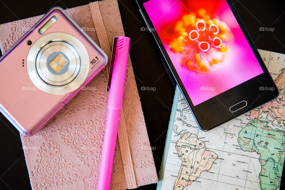 Favourite gadgets Close up of smartphone and pink camera with pink notebook travel planning book and pen