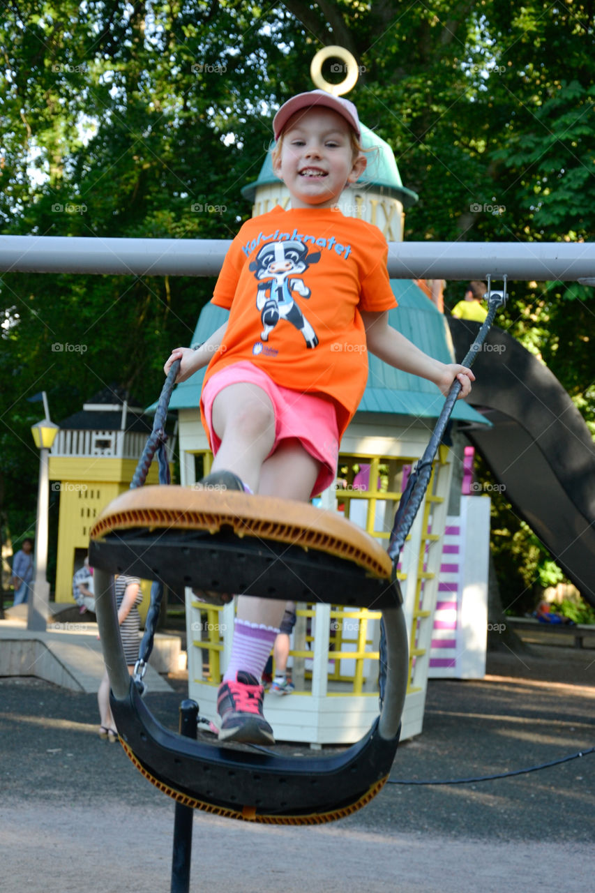 Five year old girl swining in the playground at stadsparken in Lund Sweden.