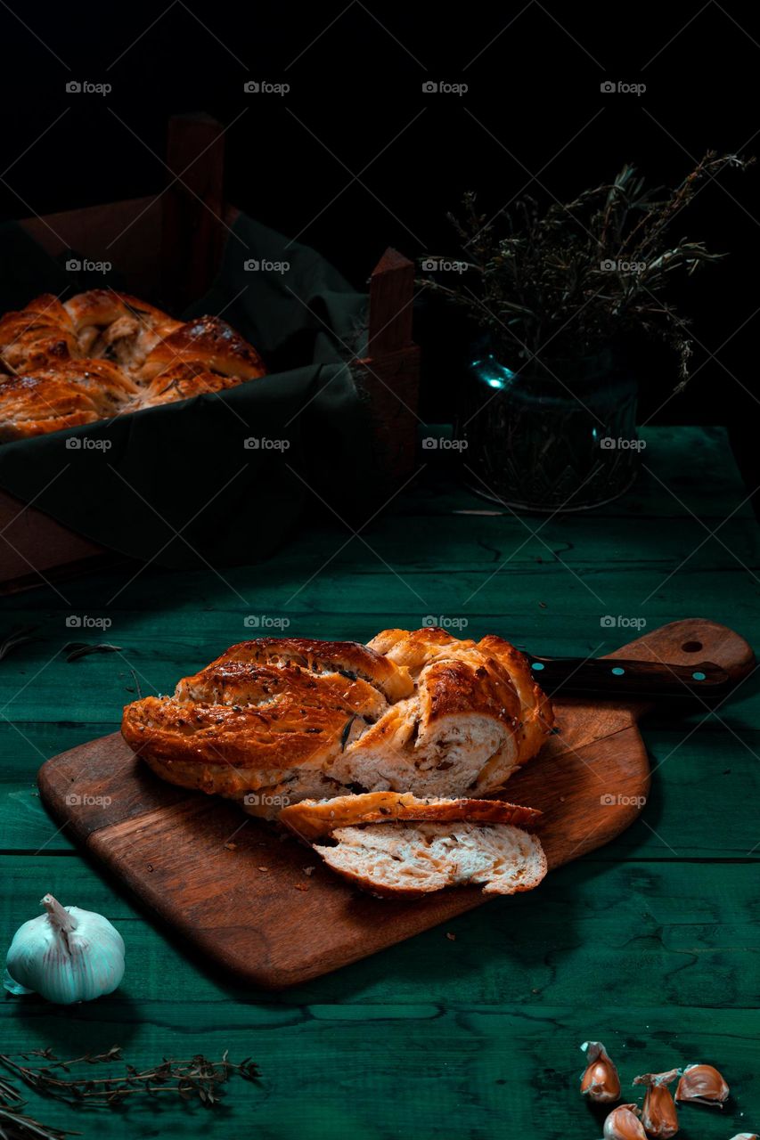 Rosemary twisted loaf bread on a green wooden background, still life, rustic style.