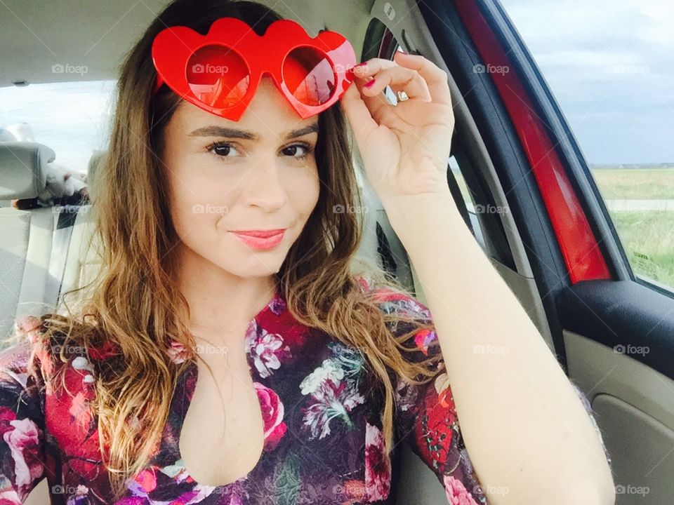 Selfie of woman in the car wearing heart-shaped sunglasses